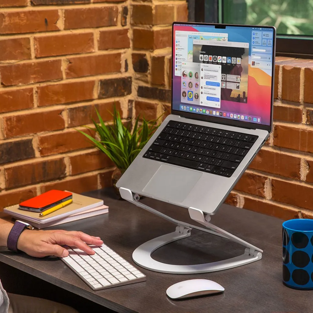 Användaren justerar MacBook på ett modernt vitt Twelve South Curve Flex-stativ för ergonomiskt skrivande och förbättrade videosamtal.