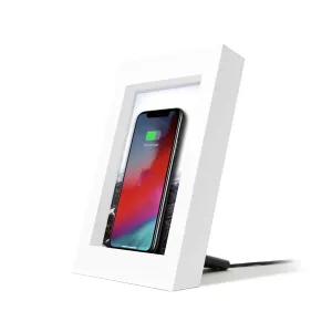 Twelve South powerPic frame trådløs oplader i hvid, med telefonen stående oprejst og under opladning i en billedramme