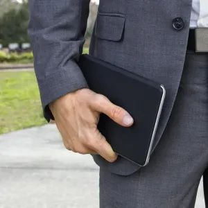 Étui pour tablette Twelve South SurfacePad au design portefeuille fin noir, tenu sur le côté par une personne en extérieur.