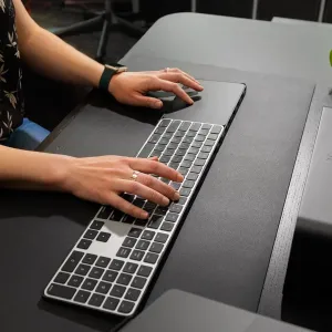 Twelve South DeskPad Schreibtischmatte aus veganem Leder in Schwarz mit Tastatur und Händen auf einem Arbeitsplatz.
