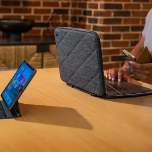 Twelve South SuitCase -kannettavan suojatasku 16 tuuman MacBook Prolle tummanharmaana, avattuna pöydällä olevan MacBookin ympärille.