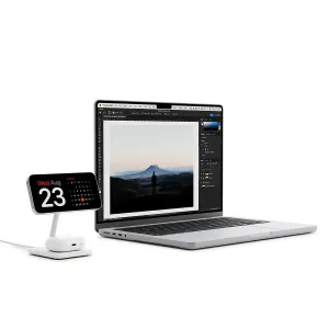 Twelve South HiRise 2 Deluxe stativ for trådløs lading med smarttelefon i liggende format ved siden av en åpen bærbar PC