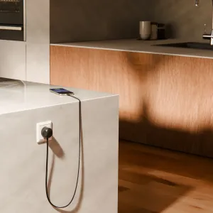 Twelve South PowerCord USB-C-laturi kytkettynä seinäpistorasiaan ja lataamassa älypuhelinta työtasolla.