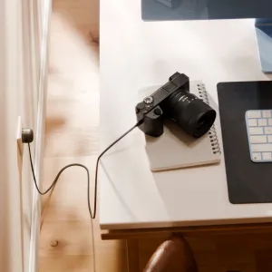 Twelve South PowerCord 1,2 m musta USB-C-laturi EU-pistokkeella liitettynä pöydällä olevaan kameraan