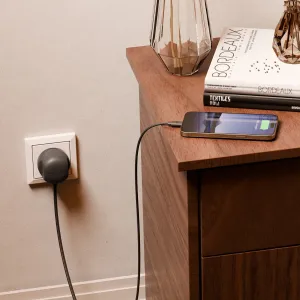Twelve South PowerCord, musta punottu USB-C-laturi kytkettynä EU-pistorasiaan ja lataamassa älypuhelinta