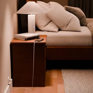 Twelve South PowerCord lataa älypuhelinta sängyn vieressä, valkoisella kaapelilla ja EU-pistokkeella.