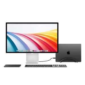 Twelve South BookArc Flex vertical laptop stand holding a MacBook upright beside a monitor