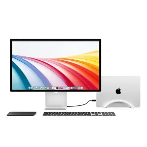 Twelve South BookArc Flex white vertical laptop stand holding a MacBook beside a desktop display
