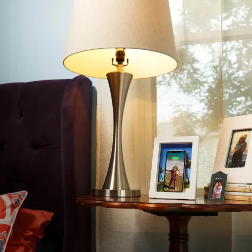 PowerPic vit fotoram med stående telefon som visar laddningsikon, placerad på sidobord bredvid bordslampa i metall.