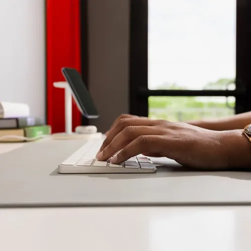 Twelve South DeskPad lysegrå skrivebordsmatte med tastatur og hender som skriver på en glatt arbeidsflate
