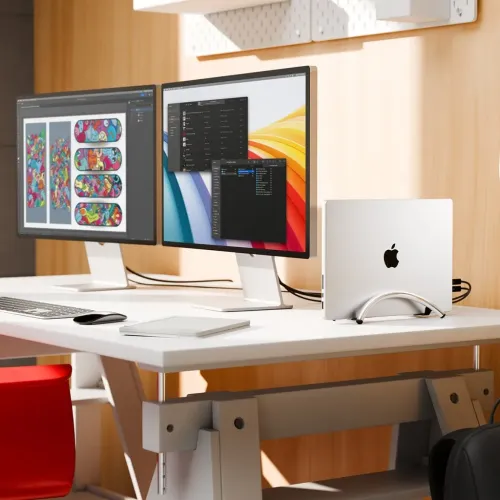 BookArc Flex-stativet i krom holder en bærbar datamaskin vertikalt på kanten av skrivebordet, med en buet bueform og svarte, stabile føtter.