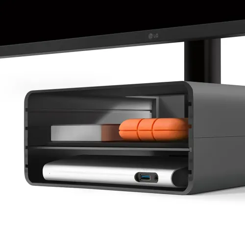 HiRise Pro iMac-stativ i gunmetal, öppet fram med avrundad profil och hyllor som visar lagringsenheter och en USB‑A‑port.