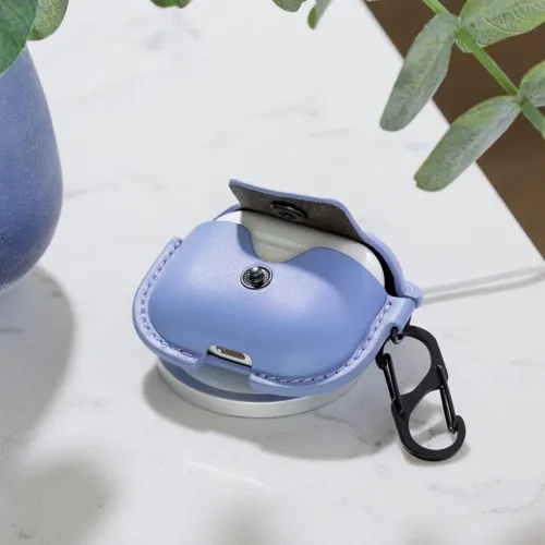 Lærveske for AirPods med åpent lokk på rund ladeplate; S-klips og utskåret Lightning-kontakt er synlige, i tillegg til gul LED.