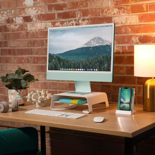 Twelve South Curve Riser, hvitt skjermstativ med buet profil og åpen hylle med myke kanter, på skrivebord med iMac på toppen.