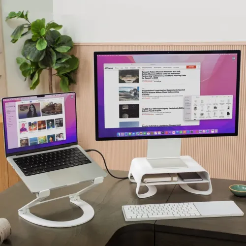 White Curve Riser under display, buet metallstativ med integrert hylle der en telefon og et tilbehør oppbevares på skrivebordet.