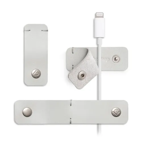 CableSnap Stay i duegrått skinn: tre kabelholdere med spor og metallknapper, hvorav den ene har plass til en hvit kabel med støpsel.