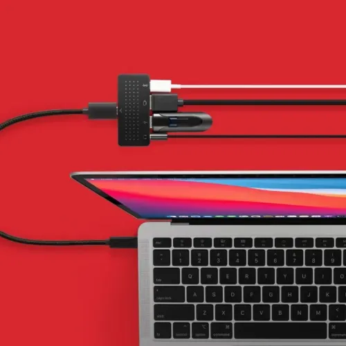 Kompakts USB-C centrmezgls ar austiņu ligzdu, USB-A, HDMI un USB-C, savienots ar klēpjdatoru, pievienoti arī kabeļi un USB atmiņas karte.