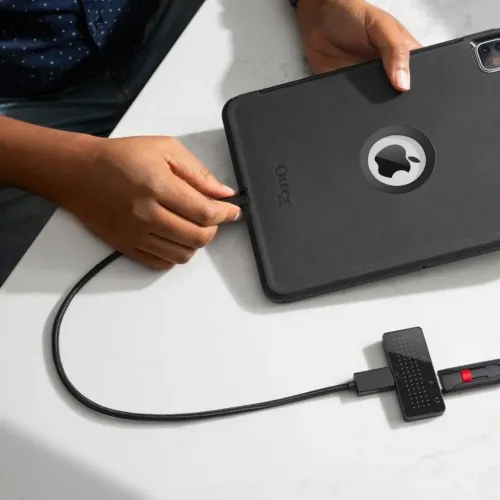 Divpadsmit South StayGo mini USB-C centrmezgls, kas ar kabeli savienots ar iPad; melna ierīce ar aizņemtu USB-A portu un citām pieslēgvietām.