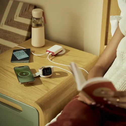 Twelve South ButterFly SE vikbar Qi2-laddare som laddar en iPhone och en Apple Watch på ett nattduksbord.