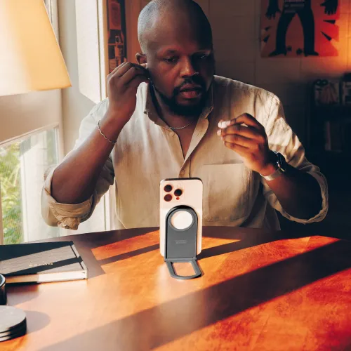 Curve Nano-stativ i skiffer med cirkulär magnetplatta och utfällbart ben håller en telefon upprätt på ett solbelyst träbord.