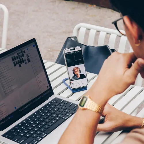 Curve Nano-telefonstativet holder smarttelefonen oppreist i stående modus på et bord, med en kompakt blå base og en lett skråstilt vinkel.